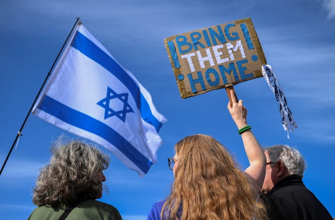 Demonstrators hold an Israeli flag and a placard calling for bringing Oct. 7 attack hostages home, in Berlin, Germany, on April 14, 2024.
